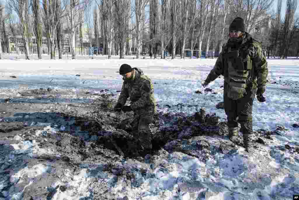 A Ukrainian soldier inspects a crater caused by an explosion in Avdiivka. Fighting between government troops and Russia-backed separatist rebels in eastern Ukraine escalated, killing at least eight people, injuring dozens and briefly trapping more than 200 coal miners underground, the warring sides reported.