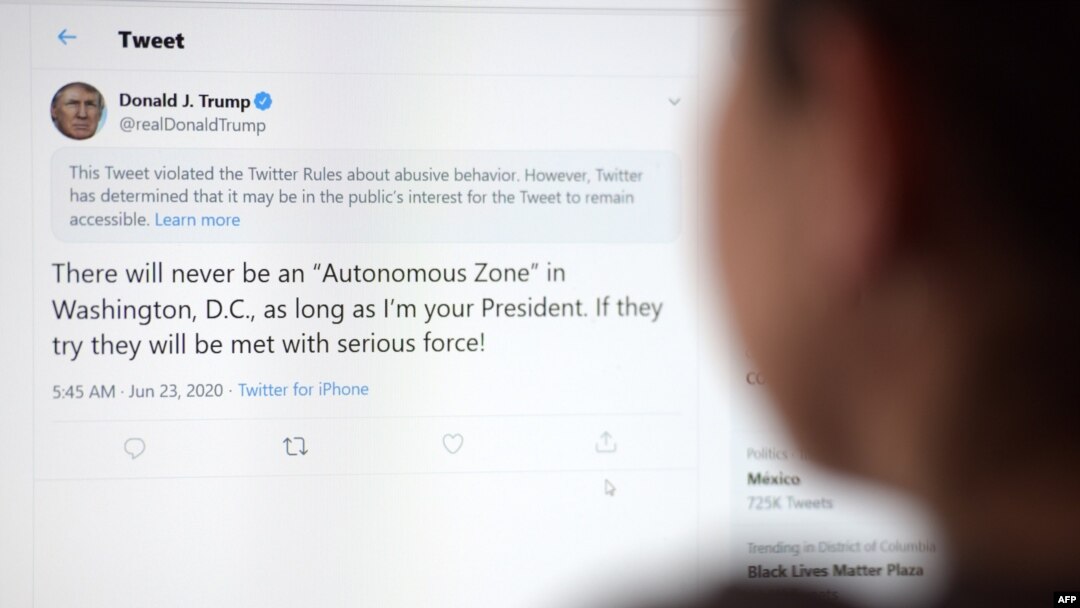 FILE - A woman in Los Angeles looks at the official Twitter account of U.S. President Donald Trump, June 23, 2020.