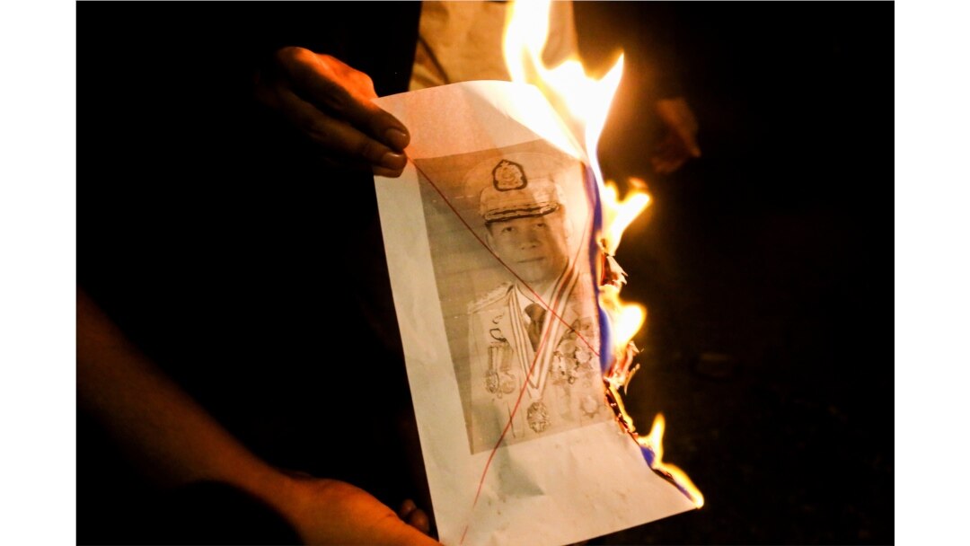 People burn a portrait of Myanmar's army chief, Min Aung Hlaing, as they protest against the military coup in Yangon, Myanmar, Feb. 5, 2021.