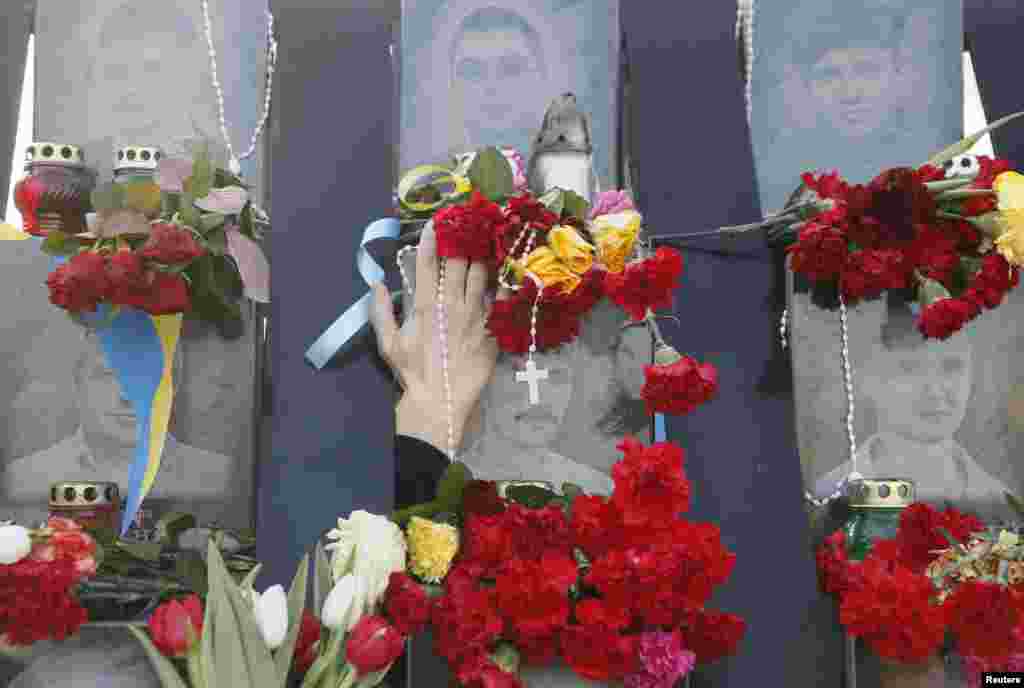A demonstrator places flowers at the monument of the so-called "Nebesna Sotnya" (Heavenly Hundred), the anti-government protesters killed during the Ukrainian pro-European Union (EU) mass protests in 2014, during a rally commemorating the third anniversary of protests, in central Kyiv.
