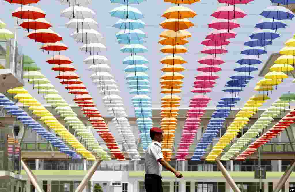 A security guard walks under the floating umbrella decorations at a commercial business park in Rawang outside Kuala Lumpur, Malaysia.