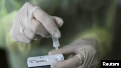 FILE - A health care worker holds a rapid COVID-19 antigen test at a coronavirus testing center in Nice, France, Oct. 15, 2020. Millions of such kits are heading to Africa for distribution.
