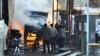 In this photo released by the Syrian official news agency SANA, Syrian citizens stand near a burning truck that was destroyed by two cars bombs in the Jermana neighborhood, a suburb of Damascus, Syria, November 28, 2012.
