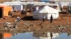 Syrian refugees sit outside their tent at their camp in Amman, Jordan, Dec. 23, 2013. 