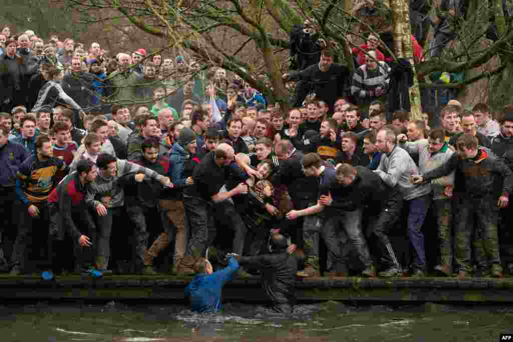 Competitors from the opposing teams, the Up'ards and the Down'ards, reach for the ball during the annual Royal Shrovetide Football Match in Ashbourne, northern England.
