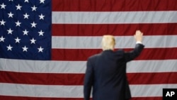 FILE - President Donald Trump waves in front of an American flag as he leaves after speaking during a rally at the Kentucky Exposition Center, March 20, 2017, in Louisville, Kentucky.