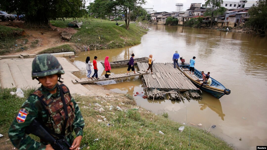 FILE - A soldier stands guard on the Thai side of the river as people prepare to cross into Malaysia in Sungai Kolok in southern Narathiwat province, March 8, 2013. 