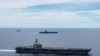 FILE - In this photo provided by U.S. Navy, the USS Ronald Reagan (CVN 76, front) and USS Nimitz (CVN 68, rear) Carrier Strike Groups sail together in formation, in the South China Sea, July 6, 2020.