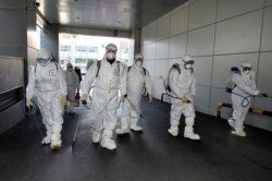 This handout picture taken Feb. 19, 2020, by Daegu Metropolitan City Namgu shows workers in protective suits spraying disinfectant in front of the Daegu branch of the Shincheonji Church of Jesus in the southeastern city of Daegu, South Korea.