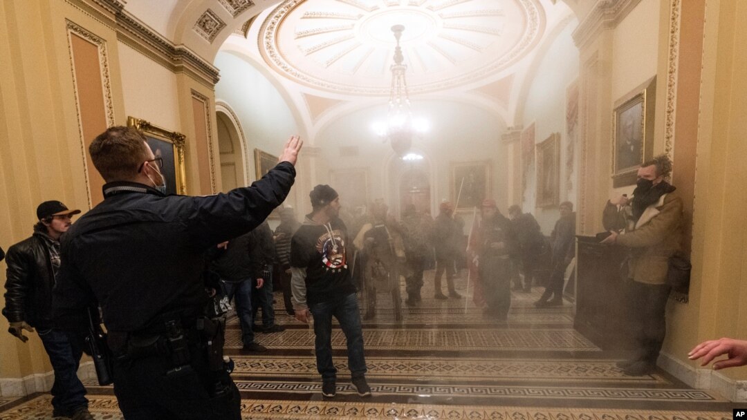 FILE - In this Jan. 6, 2021, file photo, smoke fills the walkway outside the Senate Chamber as violent rioters loyal to President Donald Trump are confronted by U.S. Capitol Police officers inside the Capitol in Washington. 