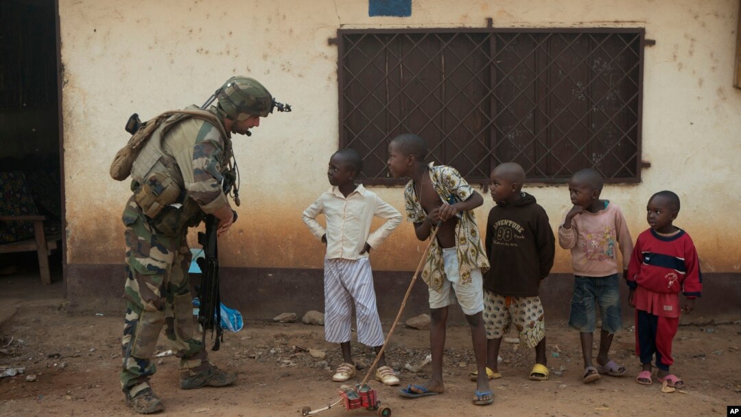 A French soldier talks to curious children as he mans a roadblock in the Miskine neighborhood of Bangui, Central African Republic, Jan. 6, 2014. 
